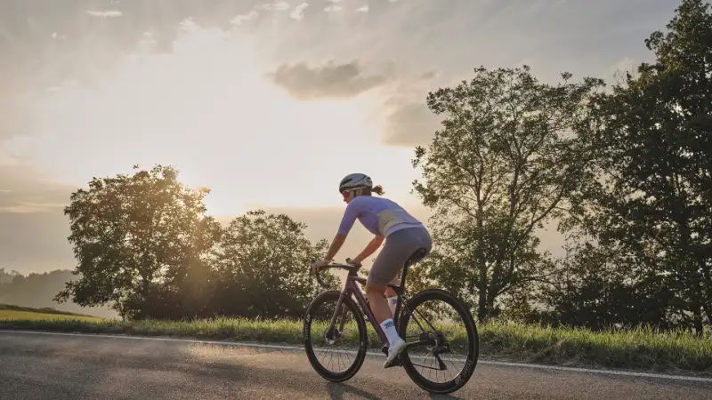 Rennradlerin fährt in den Sonnenuntergang
