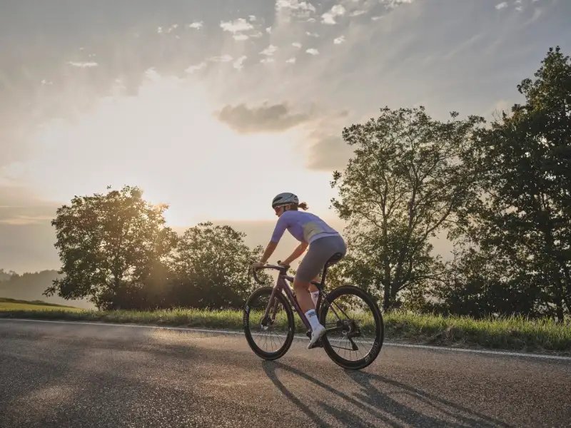 Rennradlerin fährt in den Sonnenuntergang Rennradlerin fährt in den Sonnenuntergang
